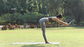 Video of a woman practicing Surya Namaskar in a park.