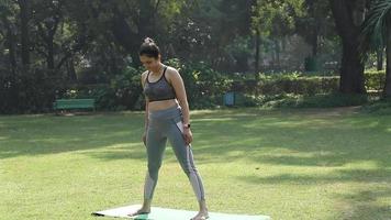 Video of a young Indian woman standing in Utthita Trikonasana pose.