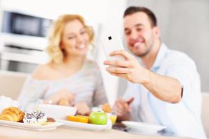 Happy couple eating breakfast and taking selfie photo