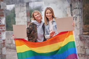 pareja lgbt con tablero de mensajes en blanco y bandera foto