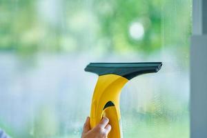 Young woman cleaning window int he kitchen photo