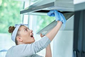 mujer joven limpiando la suciedad en la cocina foto