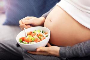 Happy pregnant woman eating salad photo