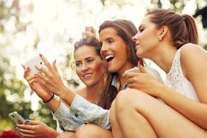 Group of girlfriends using smartphone outdoors photo