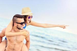 pareja joven señalando algo en la playa foto