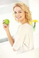 mujer joven comiendo manzana en la cocina foto