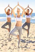 Group of women practising yoga on the beach photo