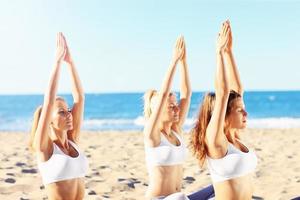 grupo de mujeres practicando yoga en la playa foto