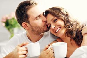 Young couple drinking coffee in bed photo