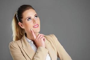 Businesswoman thinking over grey background photo