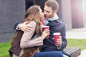 Young couple sitting on bench with coffee photo