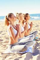 grupo de mujeres practicando yoga en la playa foto