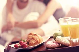 Young couple eating breakfast in bed photo