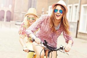 Two girl friends riding tandem bicycle photo