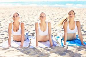 Group of women practising yoga on the beach photo