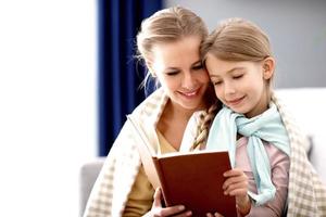 Beautiful mom and her daughter reading at home photo