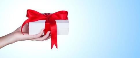 Woman holding a gift box in a gesture of giving. photo