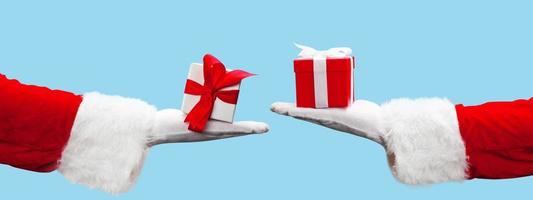 mano de santa claus sosteniendo un regalo de navidad envuelto. foto