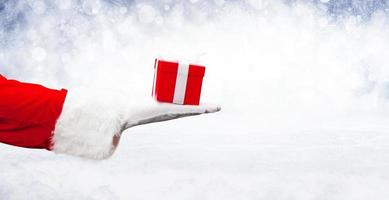 mano de santa claus sosteniendo un regalo de navidad envuelto. foto