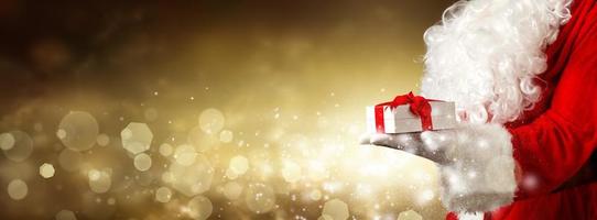 mano de santa claus sosteniendo un regalo de navidad envuelto. foto