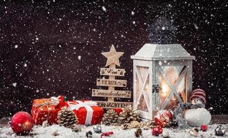Linterna de Navidad en mesa nevada con decoración festiva. foto