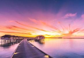 Maldives island sunset. Water bungalows resort at islands beach. Indian Ocean, Maldives. Beautiful sunset landscape, luxury resort and colorful sky. Artistic beach sunset under wonderful sky photo