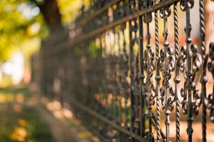 Steel fence, fragment of forged metal products with blurred nature background photo