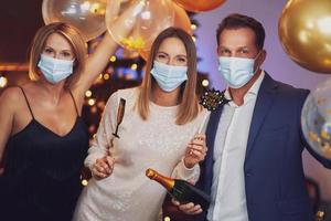 Young nice friends celebrating new year party in masks photo