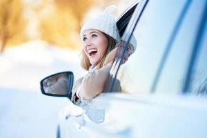 mujer feliz conduciendo un coche en invierno cubierto de nieve foto