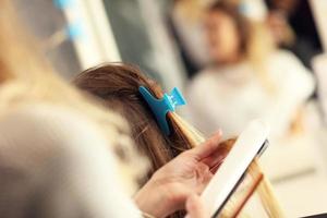 Hairdresser using hair straightener in studio photo