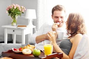 Young couple eating breakfast in bed photo