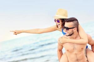 pareja joven señalando algo en la playa foto