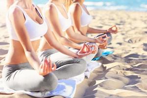 Group of women practising yoga on the beach photo