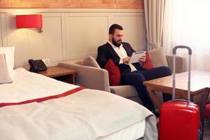 Young businessman sitting in hotel room with tablet photo