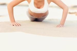 mujer haciendo flexiones en la playa foto