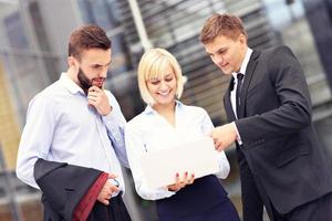 Group of business people standing outside modern building with computer photo