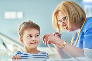 médico pediatra que examina a los niños pequeños en la revisión de los oídos de la clínica foto