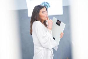 Young nice brunette woman in the bathroom with weight scale photo