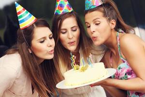 grupo de amigos soplando velas en el pastel foto