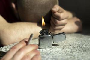 Gasoline lighter burns on table. Fire in background of sleeping guy. Party details. photo