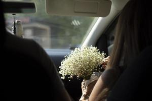 Bouquet of flowers in car. Bride's bouquet is in hands of girl. White flowers in hand. photo