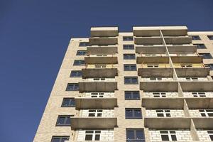 Facade of building. Unfinished house. Windows in new multi-storey building. Plastic windows on street. photo