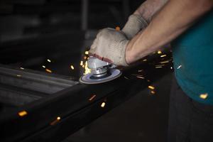 Metal processing. Grinder in hand. Worker holds tool. Creation of steel structure. photo