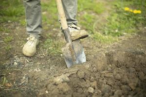 Guy is digging ground. Man with shovel. Details of rural life. photo