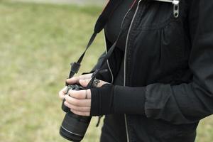 Girl with camera in black clothes. Hands hold camera. Clothing details. photo