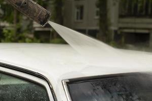 lavado de coche. lavado de suciedad de la máquina. chorro de agua a través del transporte. foto