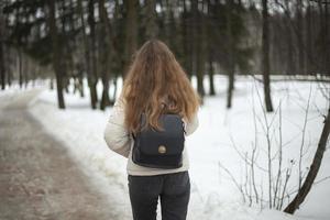 chica camina por la calle en invierno. mujer en invierno en la ciudad. mal camino en el patio en rusia. foto