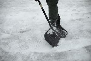 Snow shovel cleaning. Snow in yard in winter. Man cleans path from precipitation. photo