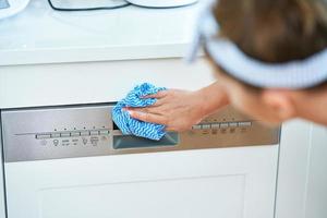 Young woman cleaning dishwasher in the kitchen photo