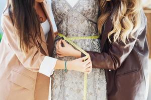 Two women tailors trying dress on mannequin photo